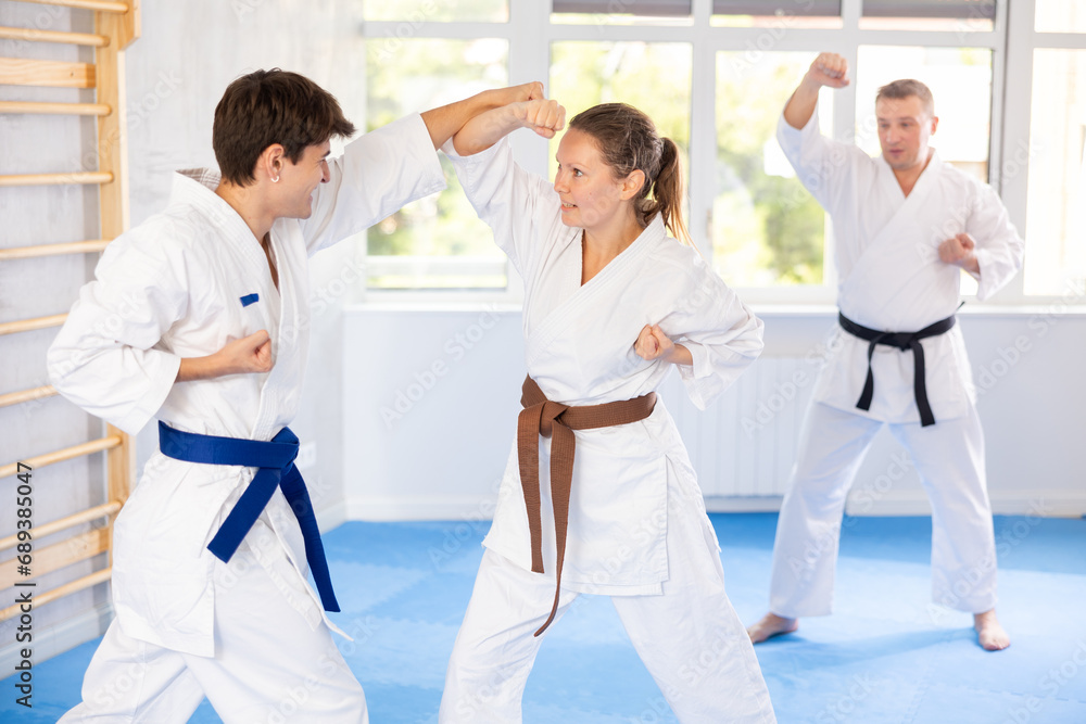 Obraz premium Guy and girl training wrestling fighting. Athletes repeat and practice basic techniques of kicks and punches. Coach prepares martial arts athletes for competitive program