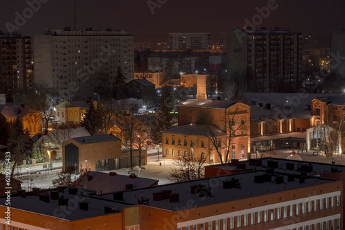 Widok miasta nocą w śniegu . Oświetlone historyczne budynki i nowoczesne bloki mieszkalne . Jesienna noc w Ostrowcu Świętokrzyskim.
