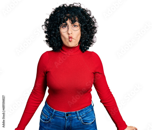 Young middle east girl wearing casual clothes and glasses making fish face with lips, crazy and comical gesture. funny expression.