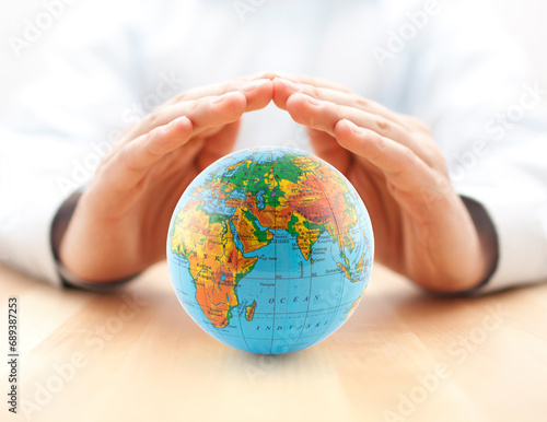 Planet Earth globe protected by hands.