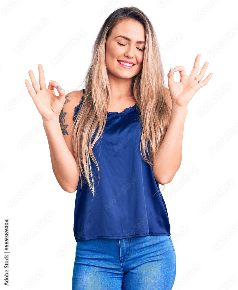 Young beautiful blonde woman wearing casual sleeveless t-shirt relax and smiling with eyes closed doing meditation gesture with fingers. yoga concept. Young beautiful blonde woman wearing casual sleeveless t-shirt relax and smiling with eyes closed doing meditation gesture with fingers. yoga concept.