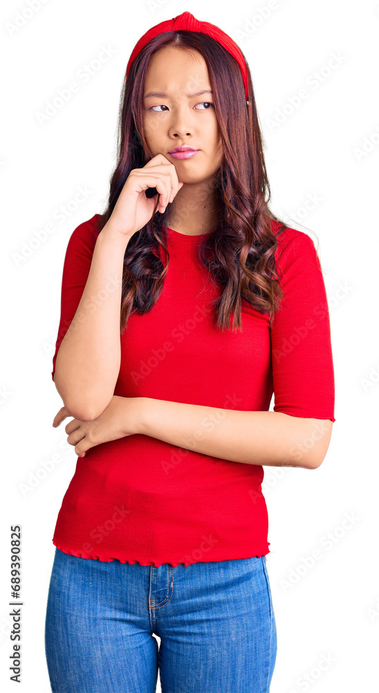 Young beautiful chinese girl wearing casual clothes and diadem serious face thinking about question with hand on chin, thoughtful about confusing idea Young beautiful chinese girl wearing casual clothes and diadem serious face thinking about question with hand on chin, thoughtful about confusing idea
