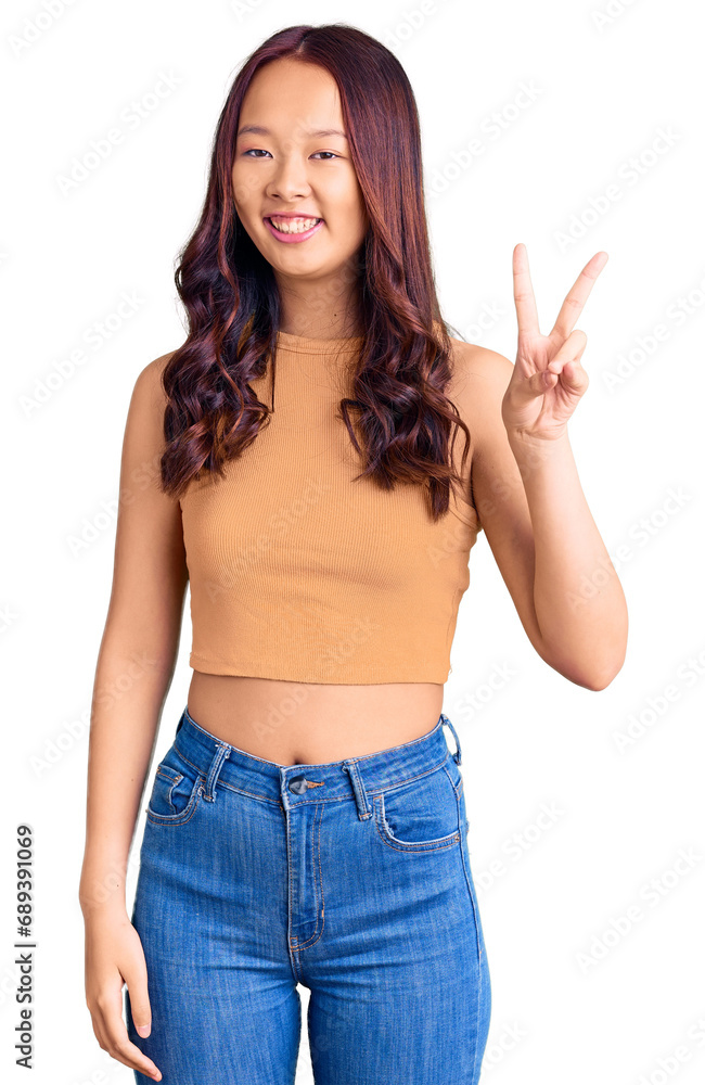 Young beautiful chinese girl wearing casual clothes smiling with happy face winking at the camera doing victory sign. number two. Young beautiful chinese girl wearing casual clothes smiling with happy face winking at the camera doing victory sign. number two.