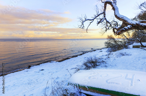 Baltic Sea coast in winter, fishing boat with an inscription on the snow 2024. Happy New Year 2021