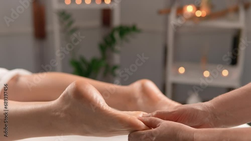 Energetic foot massage: Techniques aimed at restoring energy flow in the body, to support physical and emotional well-being in a beauty salon. Masseur kneading woman's foot photo