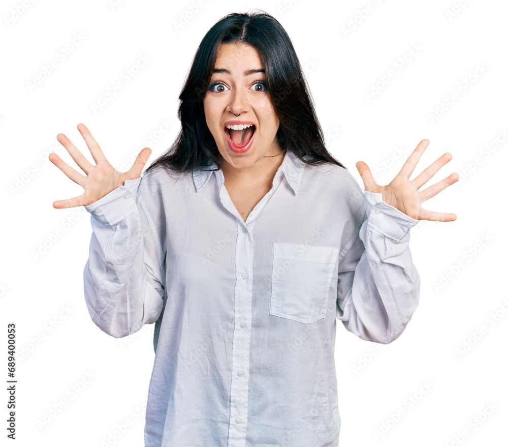 Beautiful hispanic woman wearing casual white shirt celebrating crazy and amazed for success with arms raised and open eyes screaming excited. winner concept Beautiful hispanic woman wearing casual white shirt celebrating crazy and amazed for success with arms raised and open eyes screaming excited. winner concept