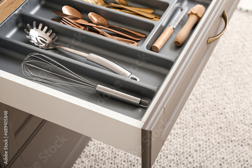Open kitchen drawer with different cutlery photo