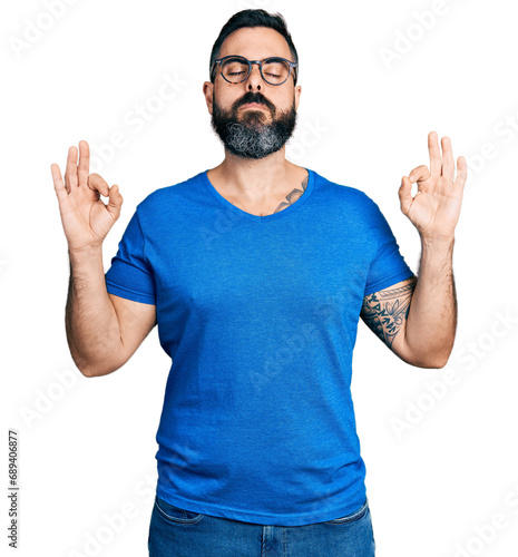 Hispanic man with beard wearing casual t shirt and glasses relax and smiling with eyes closed doing meditation gesture with fingers. yoga concept.