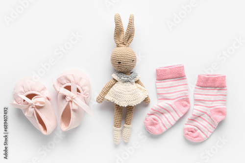 Knitted toy with baby socks on white background