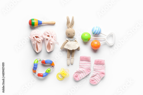 Knitted toy with baby socks and rattles on white background