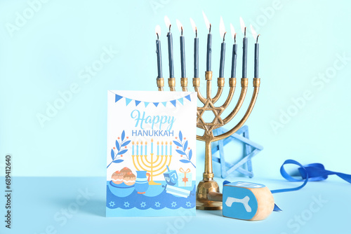 Menorah with dreidel and greeting card on blue background. Hanukkah celebration