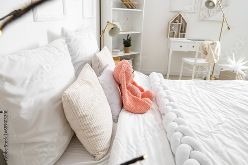 Cozy bed with plush bunny toy in children's bedroom photo