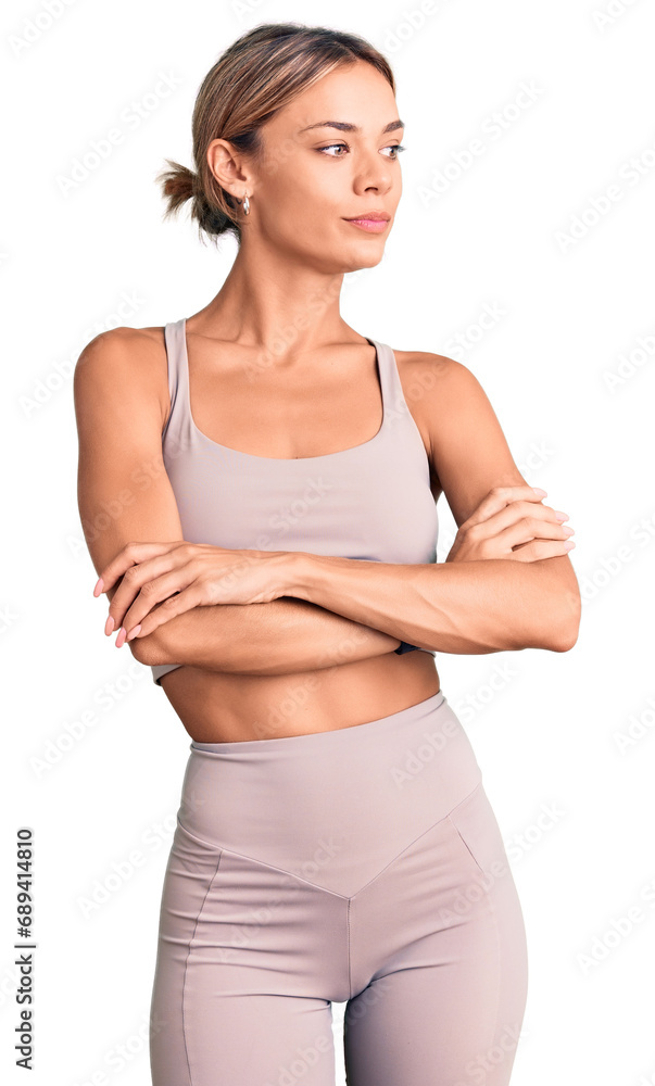 Beautiful caucasian woman wearing sportswear looking to the side with arms crossed convinced and confident Beautiful caucasian woman wearing sportswear looking to the side with arms crossed convinced and confident