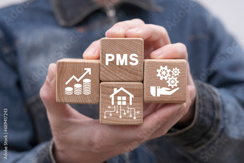 Man holding wooden blocks with icon sees abbreviation: PMS. Property Management System ( PMS ) concept related to apartment, hotel and hospitality management software. photo