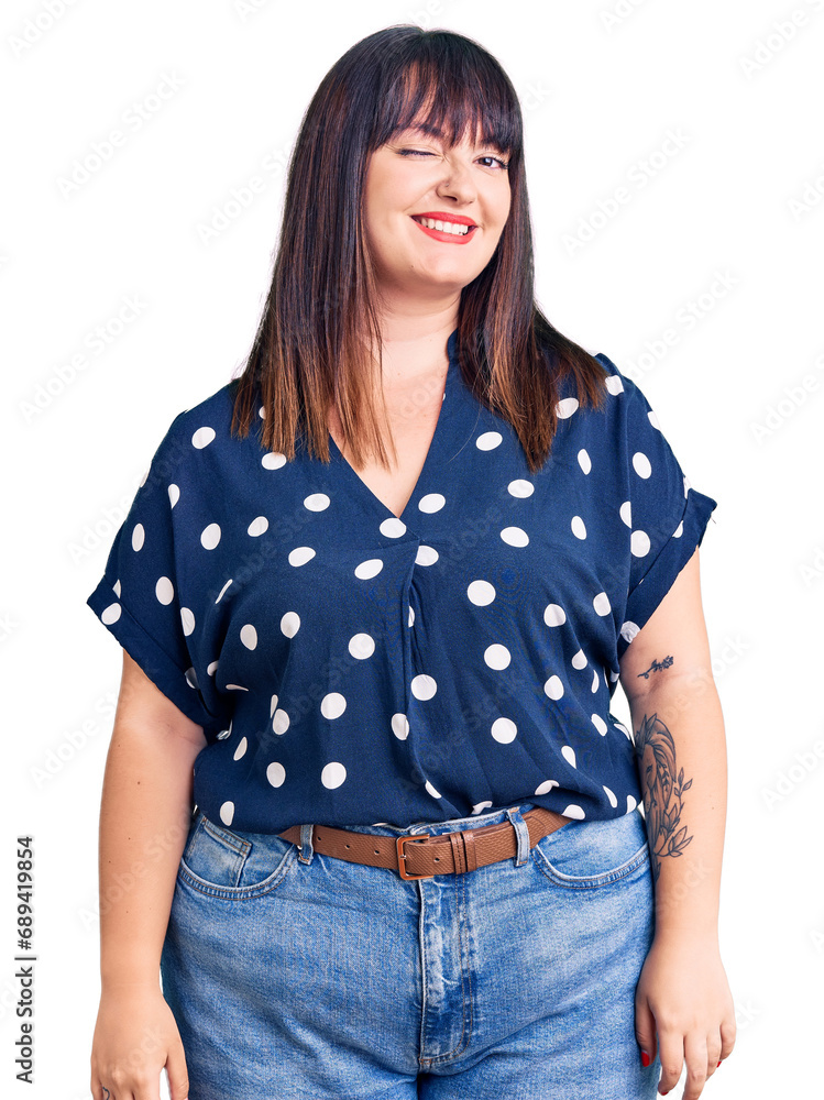 Fototapeta premium Young plus size woman wearing casual clothes winking looking at the camera with sexy expression, cheerful and happy face.