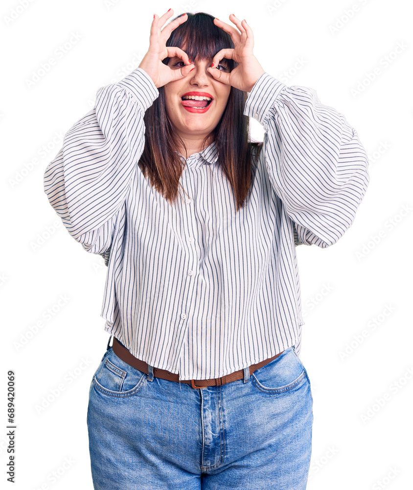 Fototapeta premium Young plus size woman wearing casual clothes doing ok gesture like binoculars sticking tongue out, eyes looking through fingers. crazy expression.
