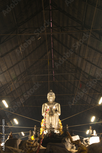 A large silver seated Buddha statue in the Pa Lelai pose. Inside the sermon hall At the bottom, devotees can walk under it. For good fortune at Wat Tha Mai temple. Located at Samut Sakhonin Thailand. photo