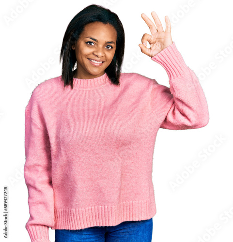 Beautiful hispanic woman wearing casual winter sweater smiling positive doing ok sign with hand and fingers. successful expression.