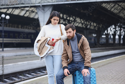 Being late. Worried couple with suitcase waiting at train station