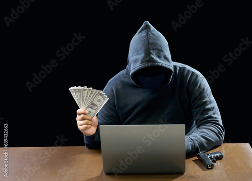 Hacker spy man wearing a black shirt, sitting on a chair and a table, is a thief, hands holding money, counting the amount obtained from hijacking or robbing, in a pitch-black room.