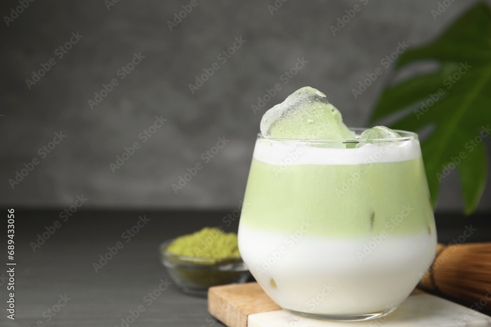 Glass of tasty iced matcha latte on grey wooden table, closeup. Space for text Glass of tasty iced matcha latte on grey wooden table, closeup. Space for text