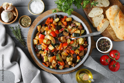 Delicious ratatouille and ingredients on grey wooden table, flat lay