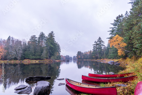 canoes on the shore of a calm reflective part of the lower madawaska river ontario in fall with autumn color room for text photo