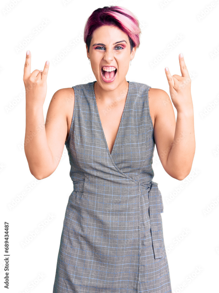 Young beautiful woman with pink hair wearing casual clothes shouting with crazy expression doing rock symbol with hands up. music star. heavy music concept. Young beautiful woman with pink hair wearing casual clothes shouting with crazy expression doing rock symbol with hands up. music star. heavy music concept.