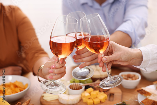 People clinking glasses with rose wine above table, closeup