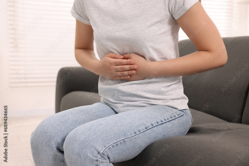 Woman suffering from abdominal pain indoors, closeup. Unhealthy stomach