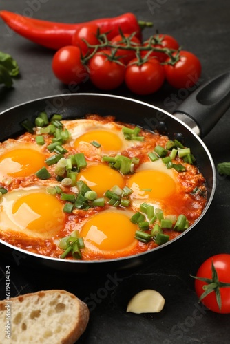 Delicious Shakshuka in frying pan served on grey textured table, closeup
