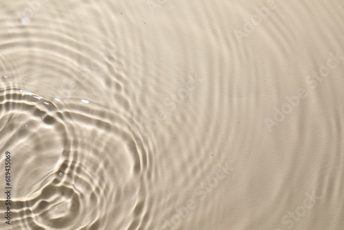 Rippled surface of clear water on beige background, top view