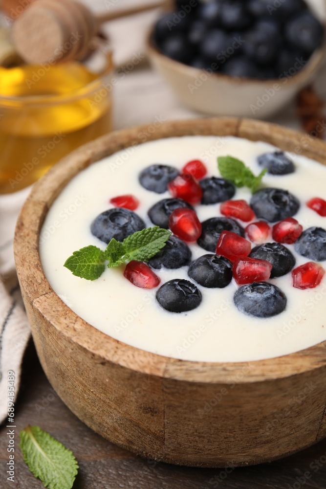 Bowl of delicious semolina pudding with blueberries, pomegranate and mint on table, closeup Bowl of delicious semolina pudding with blueberries, pomegranate and mint on table, closeup