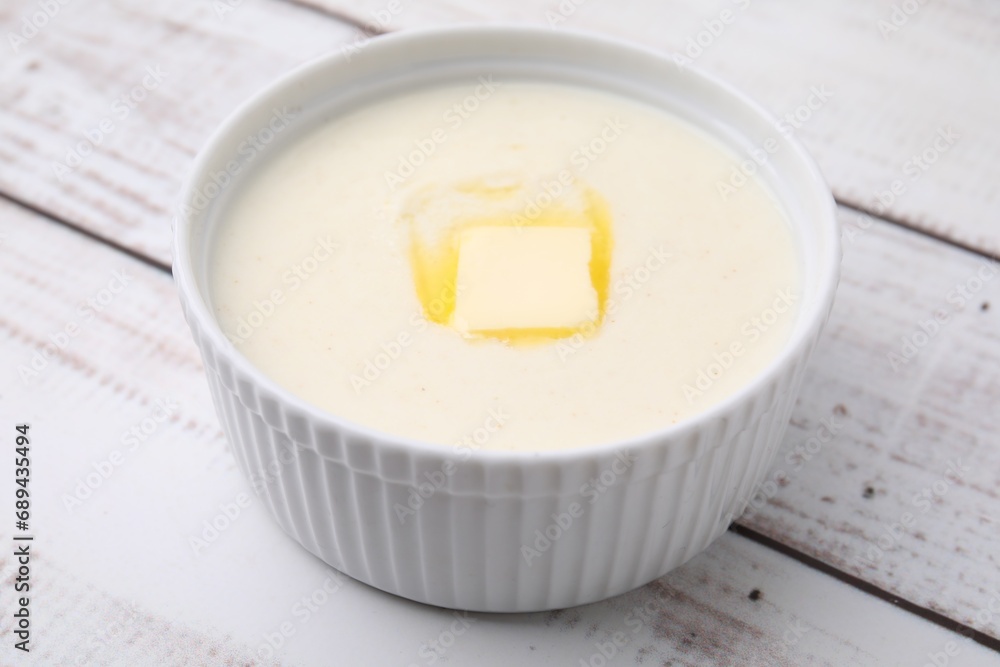 Bowl of delicious semolina pudding with butter on white wooden table, closeup Bowl of delicious semolina pudding with butter on white wooden table, closeup