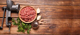Manual meat grinder, beef mince, peppercorns, onion and parsley on wooden table, flat lay. Banner design with space for text