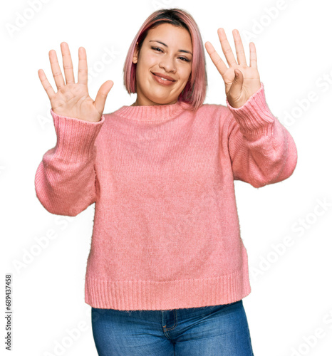 Hispanic woman with pink hair wearing casual winter sweater showing and pointing up with fingers number nine while smiling confident and happy.