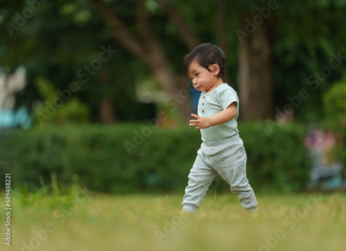 infant baby learning to walking first step on green grass in park