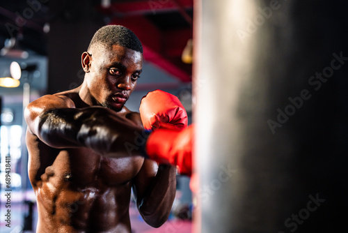 African sportsman boxer doing boxing workout in dark fitness stadium.  © Kawee