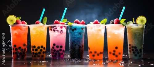 Fototapeta Naklejka Na Ścianę i Meble -  Drinks of various colors with tapioca bubbles, garnished with fruits and straws on a dark background
