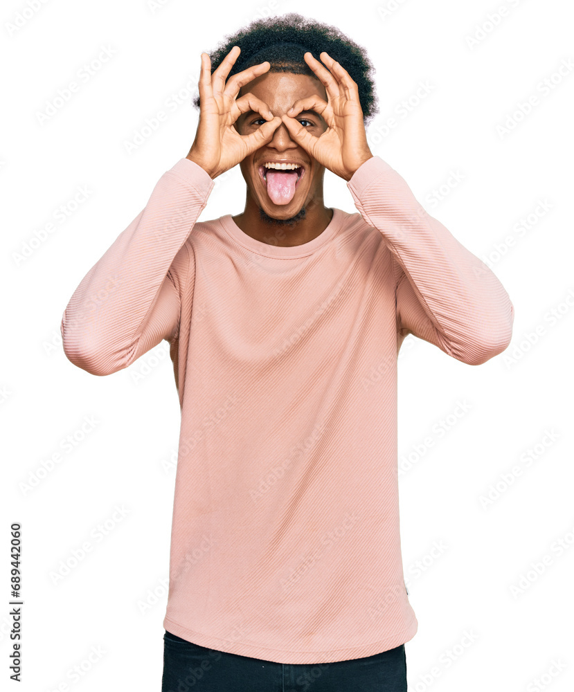 African american man with afro hair wearing casual clothes doing ok gesture like binoculars sticking tongue out, eyes looking through fingers. crazy expression. African american man with afro hair wearing casual clothes doing ok gesture like binoculars sticking tongue out, eyes looking through fingers. crazy expression.