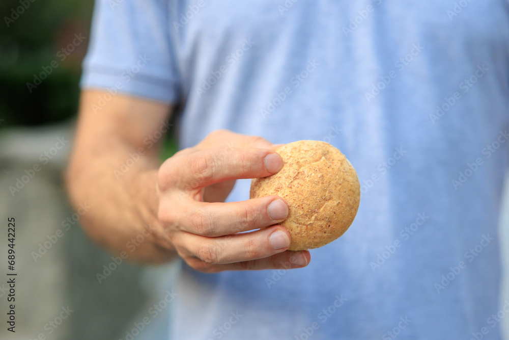 Man's hand holds mini bread, snack and fast food concept. Selective focus on hands with blurred background Man's hand holds mini bread, snack and fast food concept. Selective focus on hands with blurred background