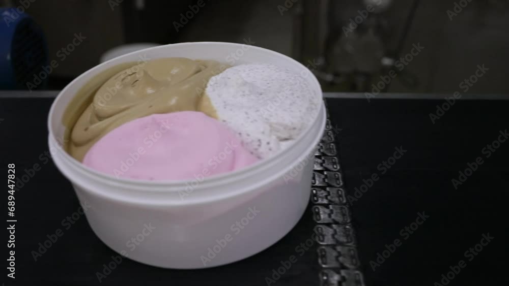 Ice cream factory. Closeup view of a conveyor belt transporting commercial ice cream pots with different flavors. Ice cream factory. Closeup view of a conveyor belt transporting commercial ice cream pots with different flavors.