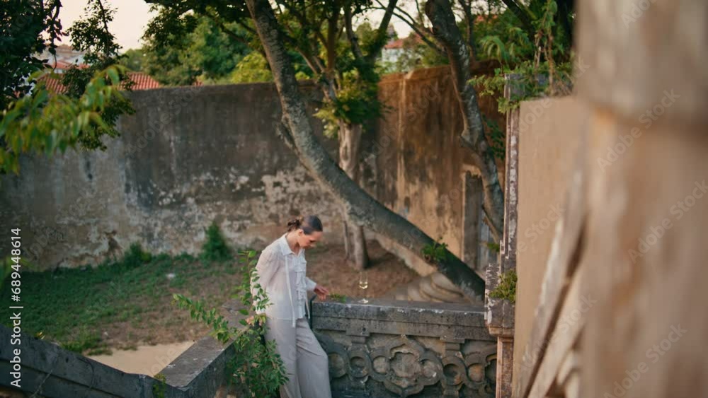 Trendy model posing ancient palace in elegant suit. Woman leaning stone railings Trendy model posing ancient palace in elegant suit. Woman leaning stone railings