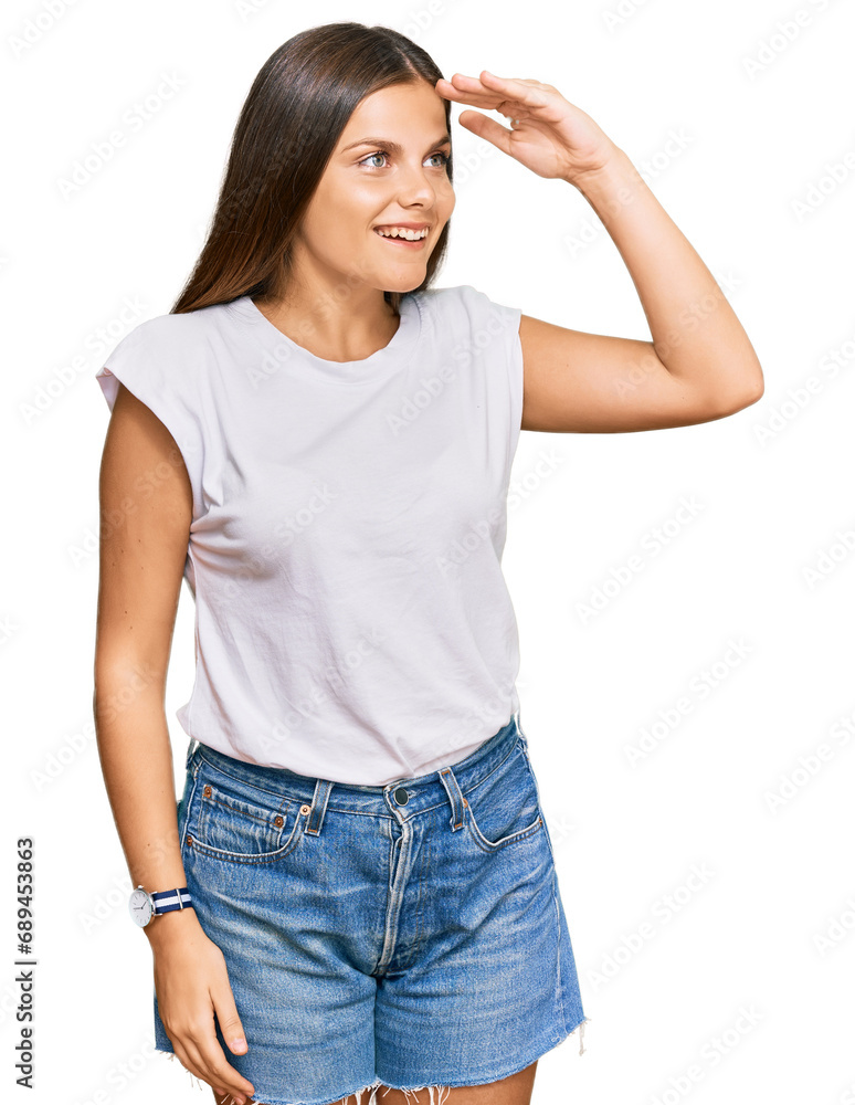 Young caucasian woman wearing casual white tshirt very happy and smiling looking far away with hand over head. searching concept. Young caucasian woman wearing casual white tshirt very happy and smiling looking far away with hand over head. searching concept.