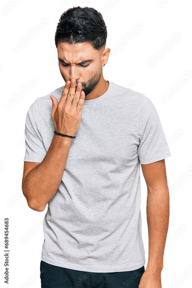 Young man with beard wearing casual grey tshirt bored yawning tired covering mouth with hand. restless and sleepiness. Young man with beard wearing casual grey tshirt bored yawning tired covering mouth with hand. restless and sleepiness.