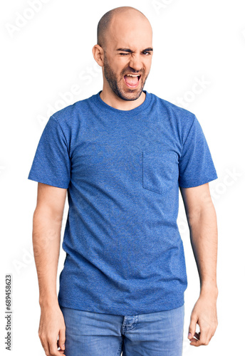 Young handsome man wearing casual t shirt winking looking at the camera with sexy expression, cheerful and happy face.