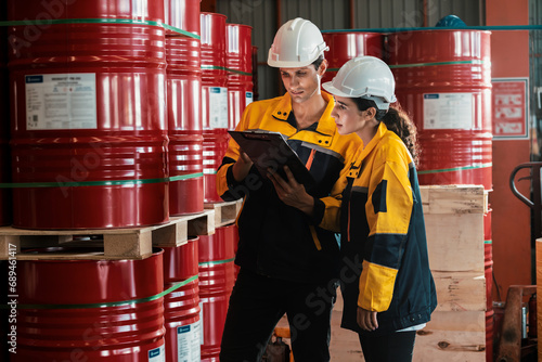Two factory workers or inventory inspector conduct professional inspection on hazardous chemical barrels in warehouse, chemistry storage workplace and industrial profession concept. Exemplifying