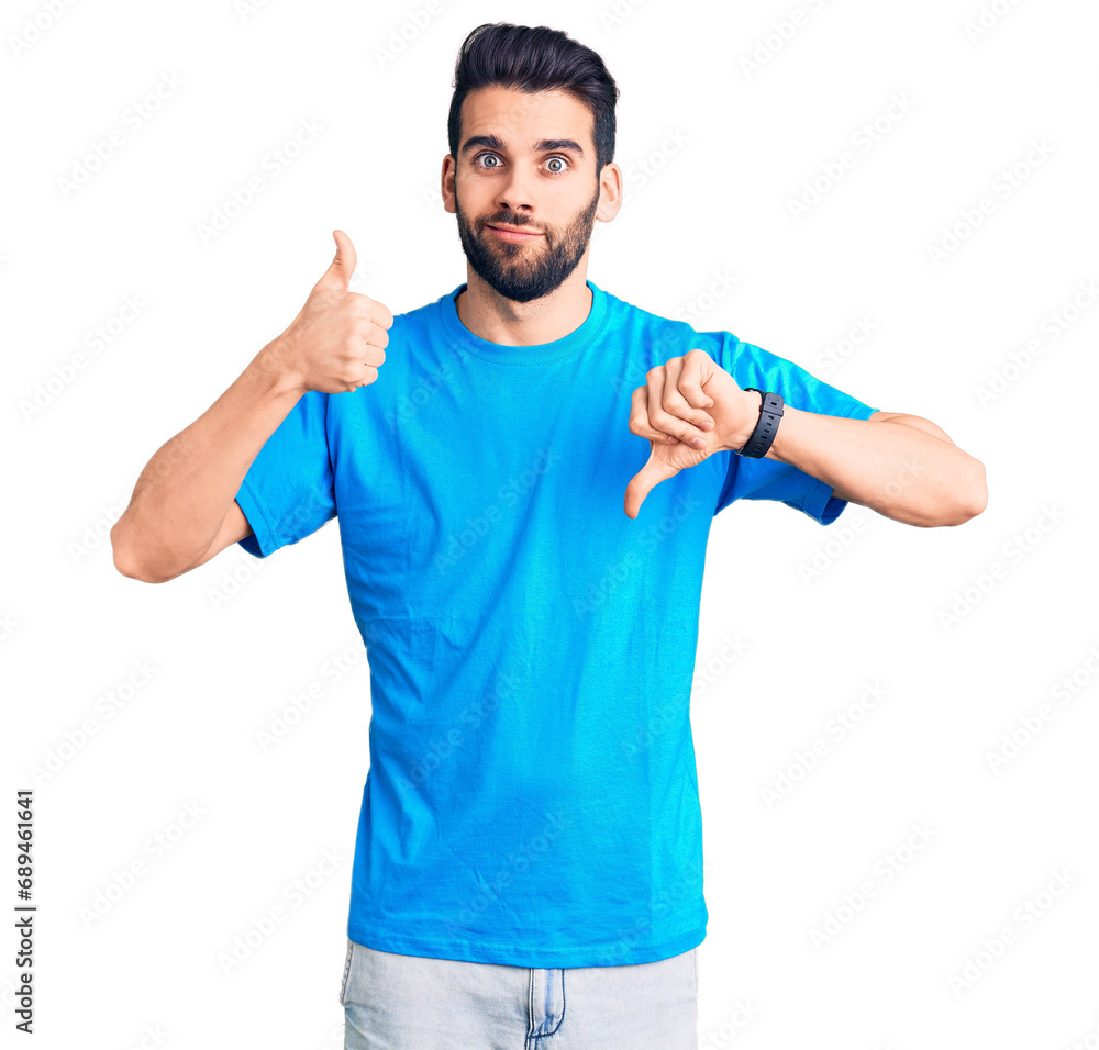 Young handsome man with beard wearing casual t-shirt doing thumbs up and down, disagreement and agreement expression. crazy conflict Young handsome man with beard wearing casual t-shirt doing thumbs up and down, disagreement and agreement expression. crazy conflict