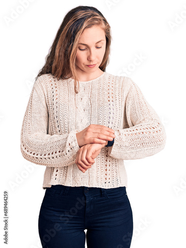 Young beautiful blonde woman wearing casual sweater checking the time on wrist watch, relaxed and confident