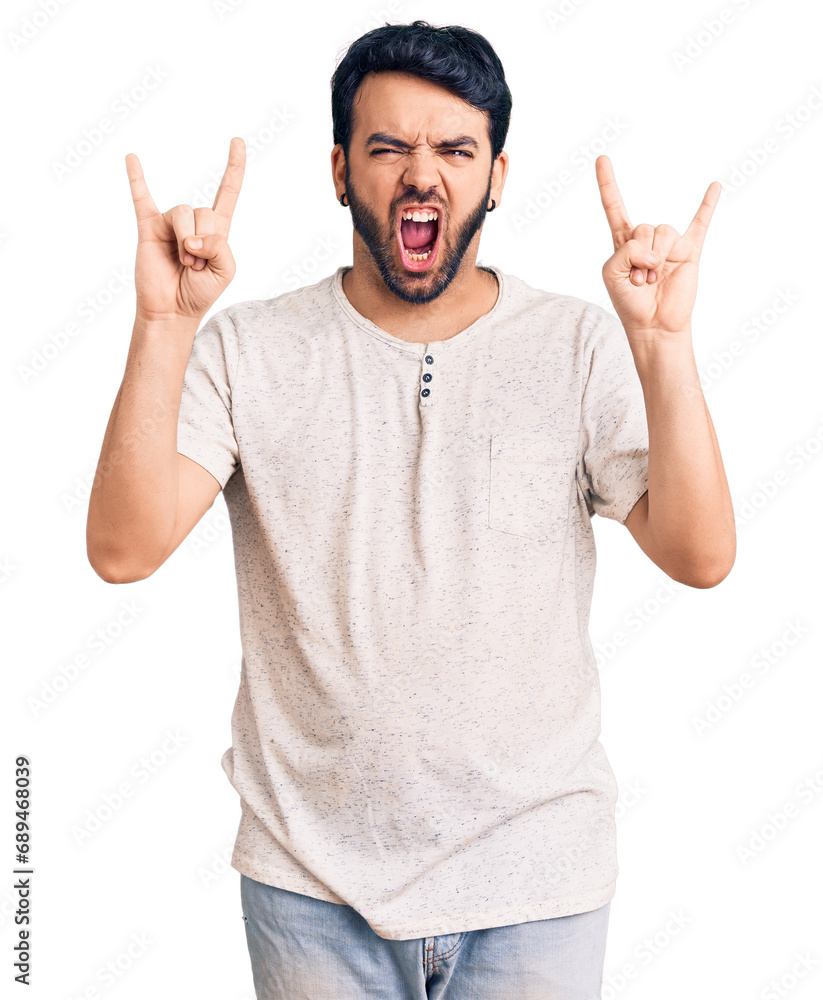 Fototapeta premium Young hispanic man wearing casual clothes shouting with crazy expression doing rock symbol with hands up. music star. heavy concept.